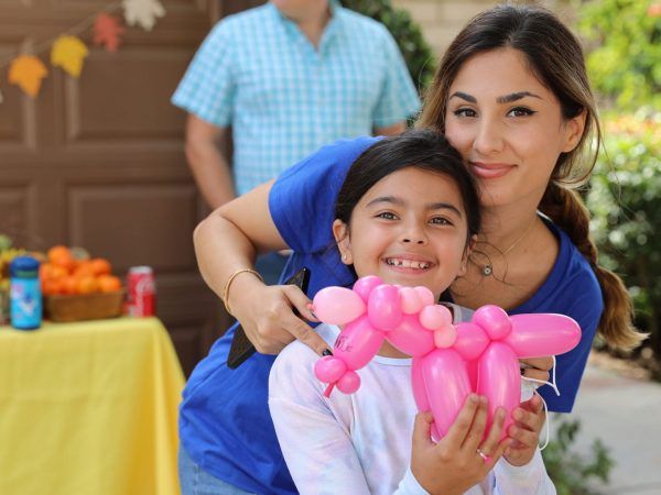 a woman and a little girl pose for a picture together with a balloon dog in her arms