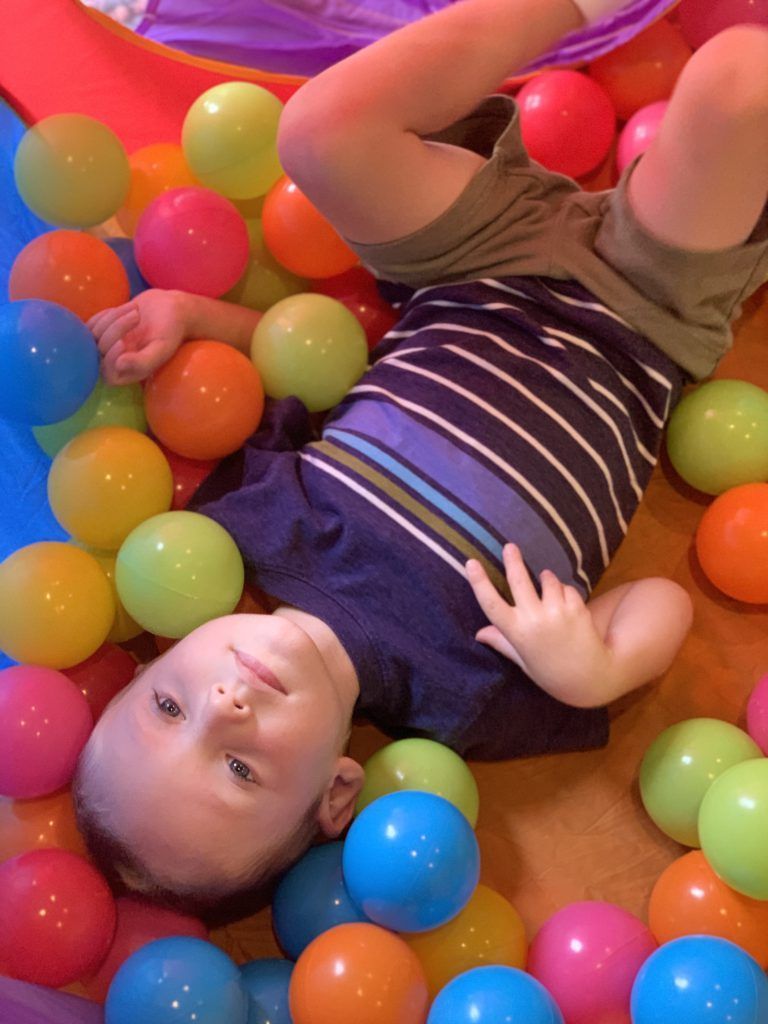 The toddler in the many colorful plastic balls.