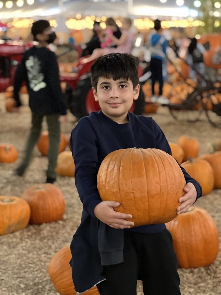Independent boy who carries an orange pumpkin.