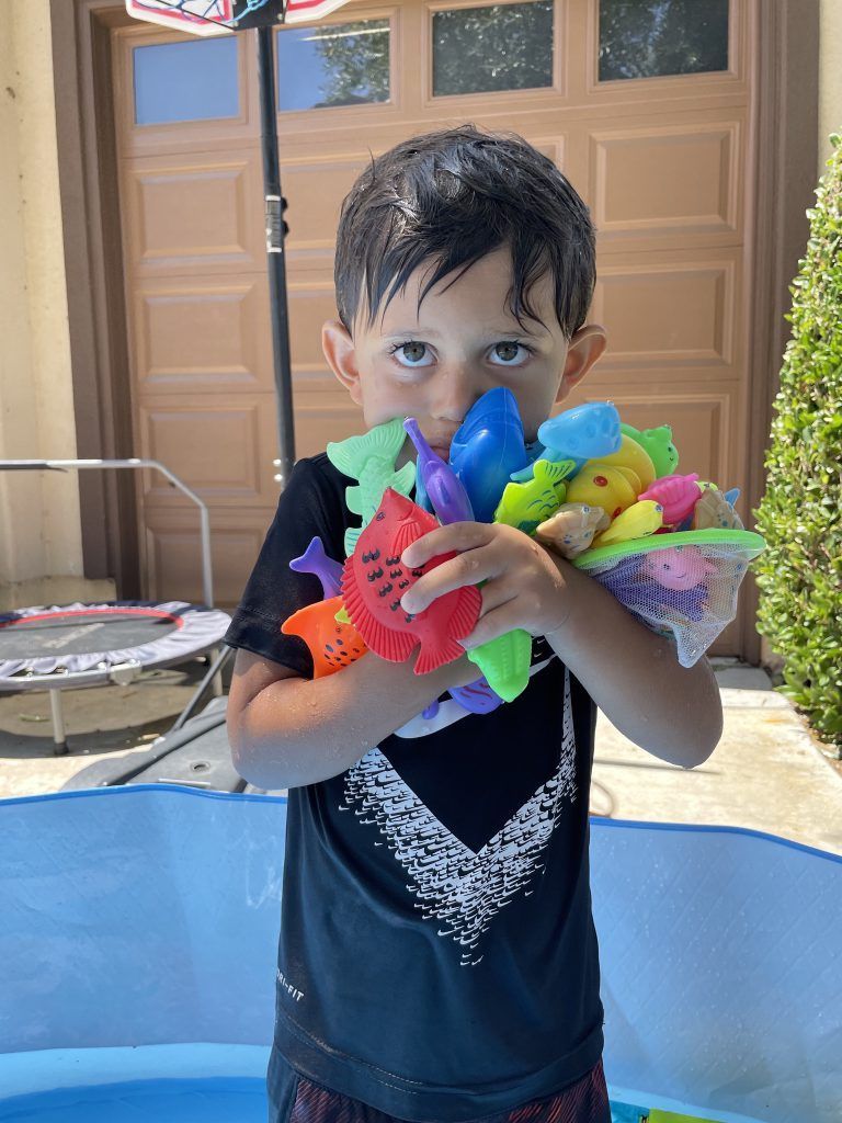 Little boy plays with plastic fishes and toys_Outdoor summer fun_Healthy activity for hot sunny days.