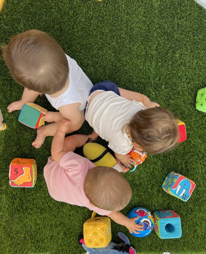 Nursery babies toddlers playing with color toys isolated on playground
