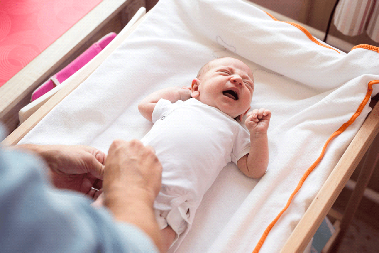 Unrecognizable father changing a diaper to his crying baby son