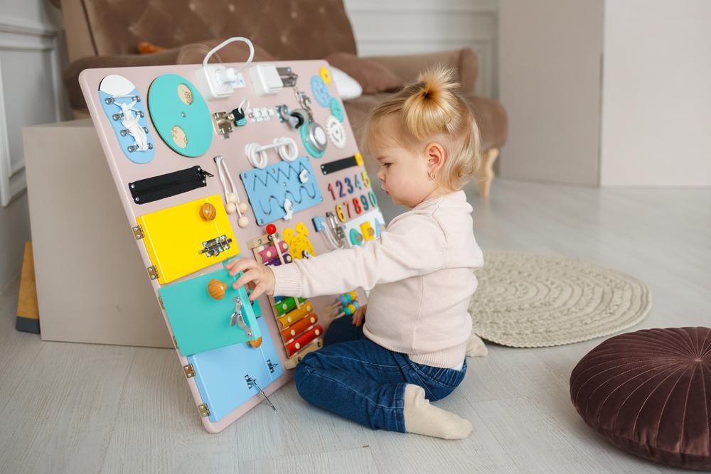 bright, Busy board for For children. Happy baby playing with the busy board. Children's educational toys. Wooden game board.