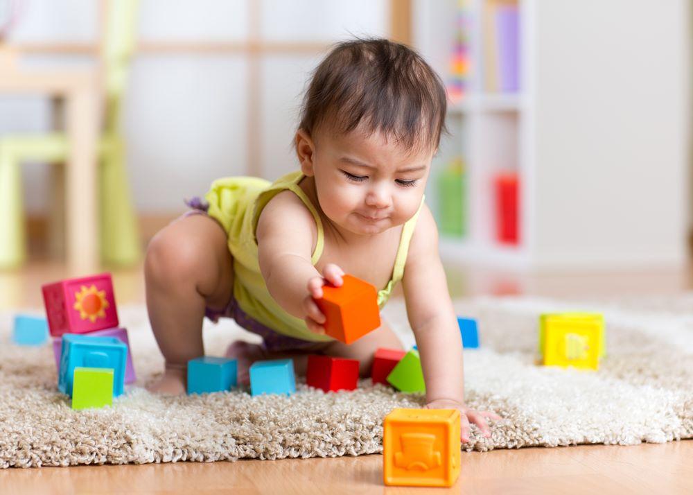 baby toddler playing with wooden toys at home or nursery