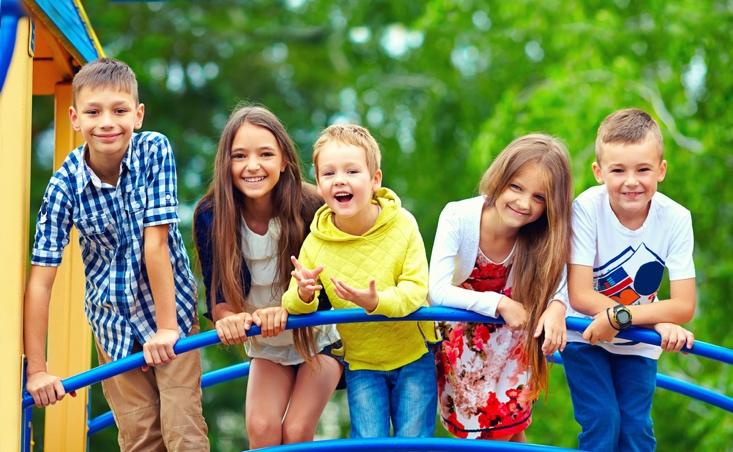 Group of small nursery school children playing outdoors on a playground.