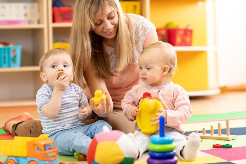babysitter and children playing together in the nursery or at home