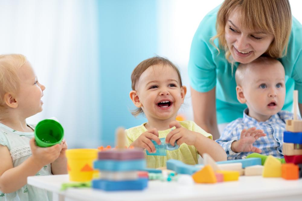 Babies play with the teacher in nursery or creche.