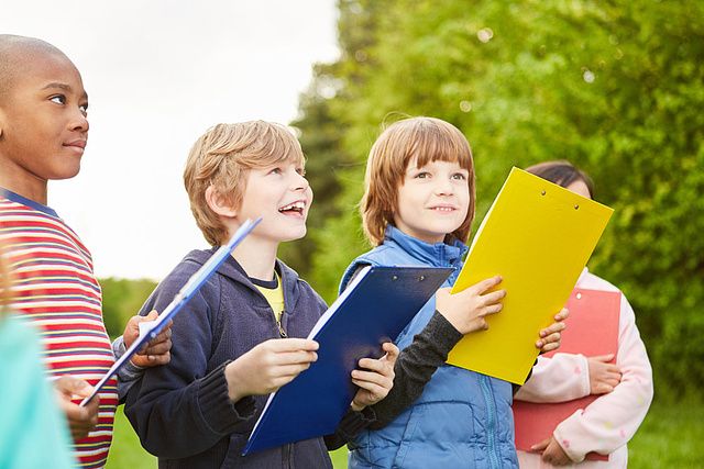 Group of kids together play scavenger hunt at kids birthday with clipboard