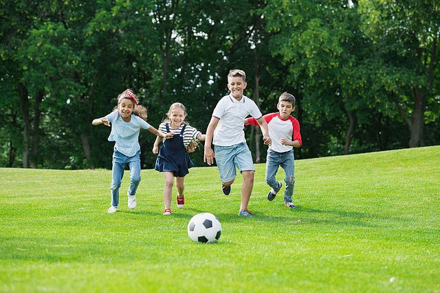 Child Playing Amateur Football. Full Shot of Young Boy Wearing Blue Football Dress Number Eight Kicking Ball at Football Field.