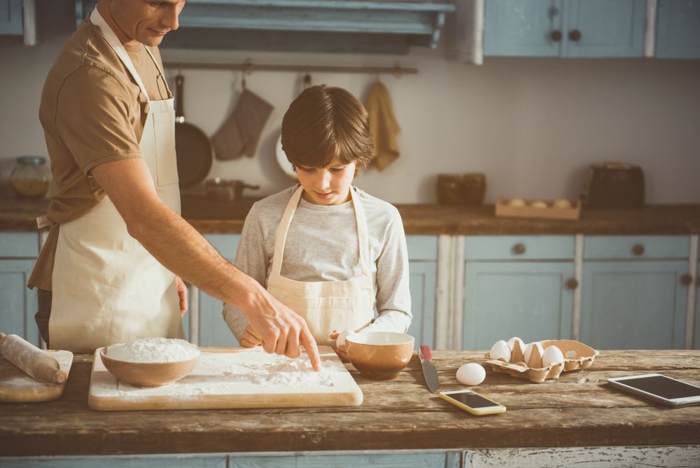 Father teaching son to cut onion in kitchen at home