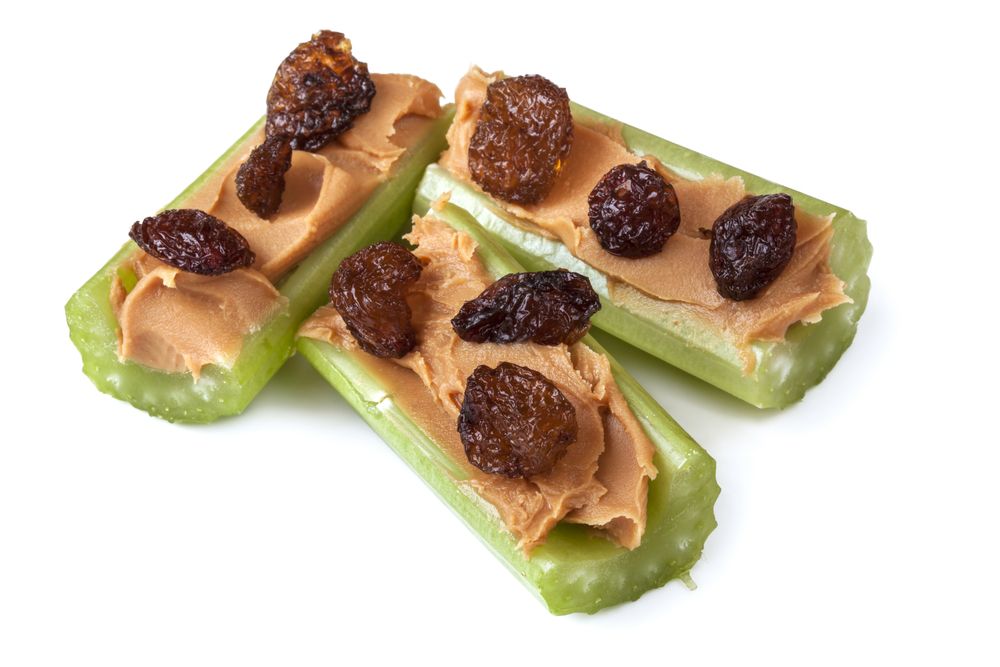 Ants on a log, celery with peanut butter and raisins, isolated on white. Healthy snacks.