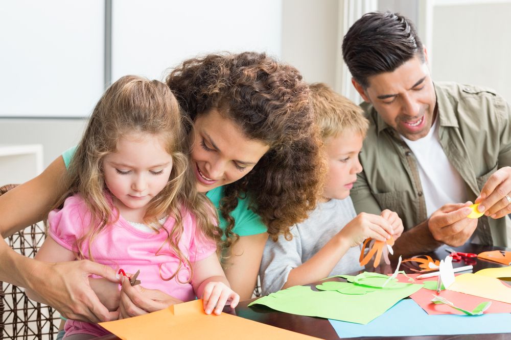  Cheerful family doing arts and crafts together at the table at home in kitchen