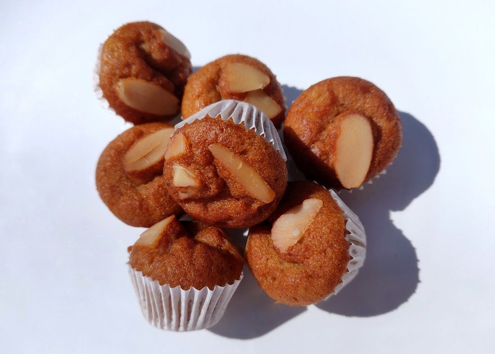 close up mini banana muffins with almonds slide on white plate