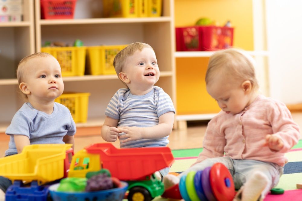 Little toddlers boys and a girl playing together in kindergarten or creche. Preschool children in day care centre 