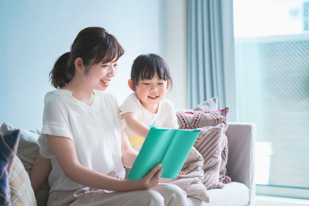 Mother and daughter sitting on the sofa and reading a picture book