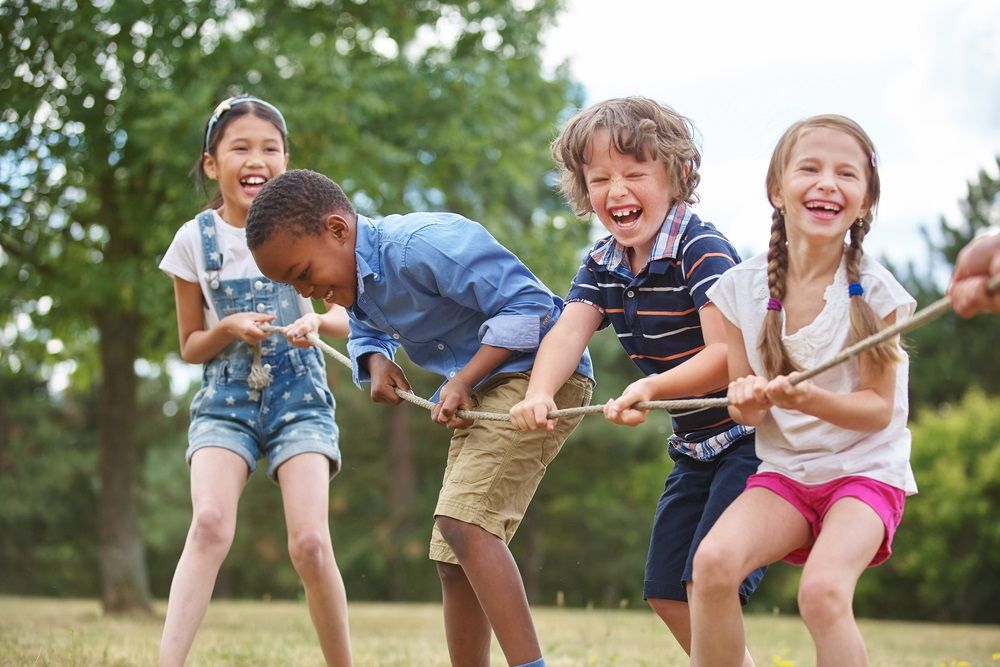 Group of cute little children laughing and high fiving together while having a fun in a bouldering gym