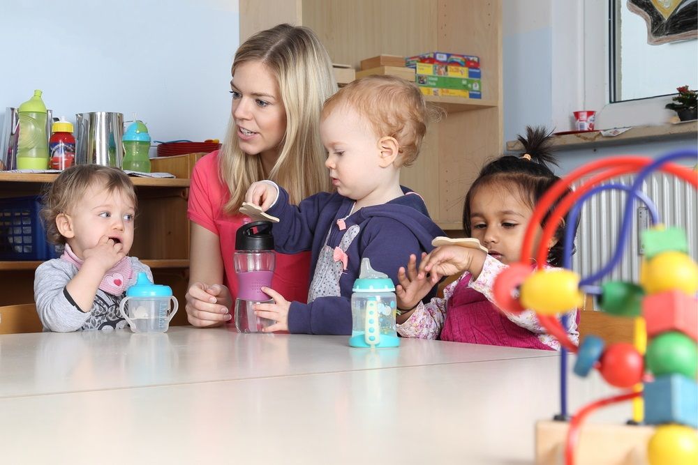 Some Kindergarten or nursery kids on a table drinking and playing