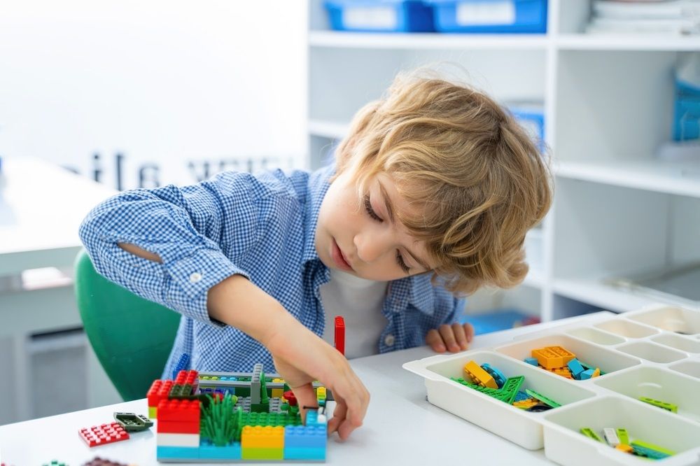 Robotics programming class. Children construct and code Robot. STEM education using constructor blocks and laptop, remote control joystick. Technology educational development for school kids