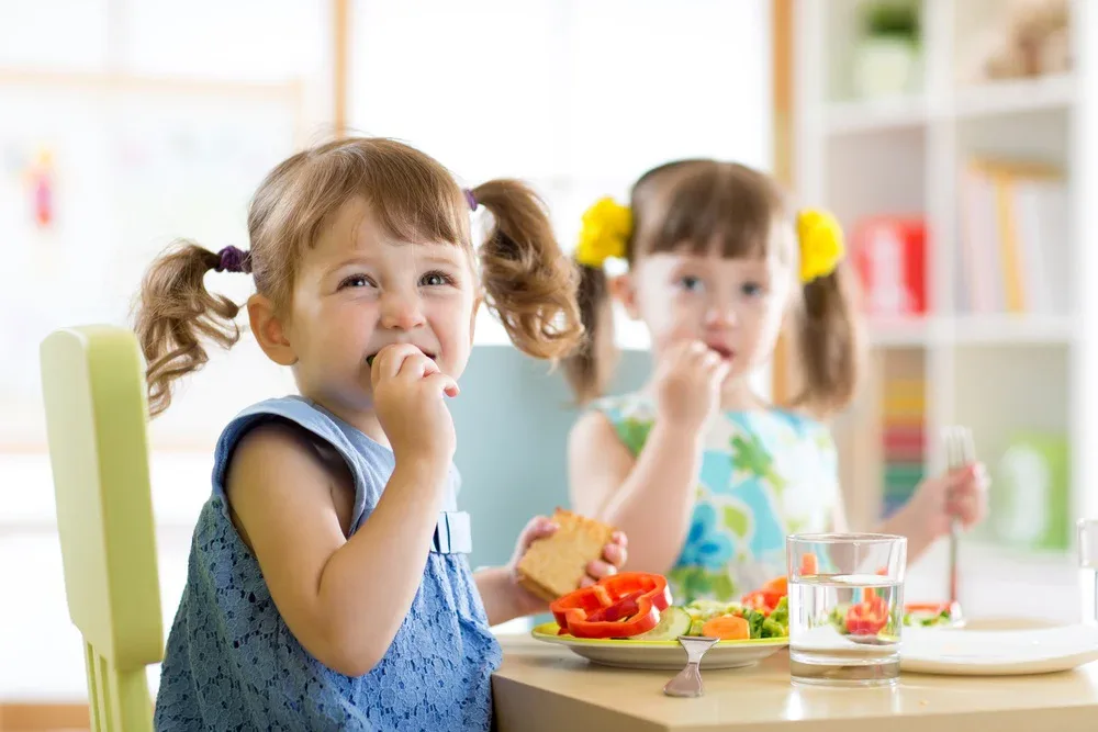Cute little children eating food at daycare centre