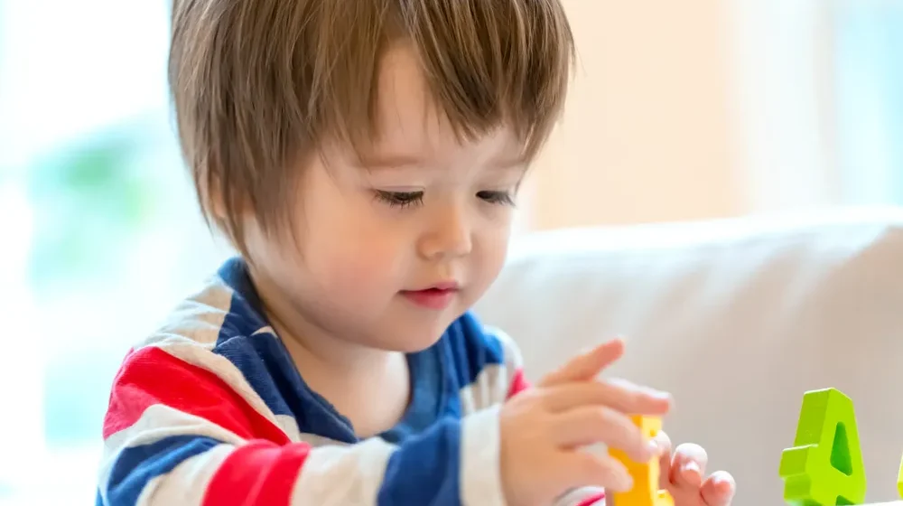 Toddler development program in Irvine with children building colorful blocks during supervised play-based learning