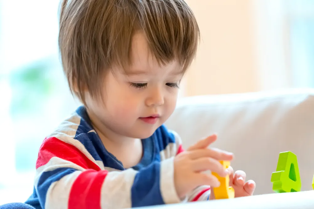 Toddler development program in Irvine with children building colorful blocks during supervised play-based learning