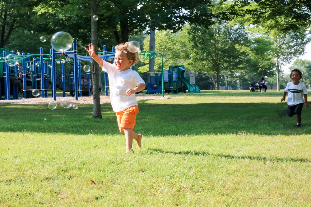 Preschool children chasing bubbles during safe outdoor active play in Irvine 